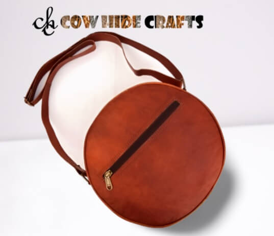 Adjustable shoulder strap on tan leather round crossbody bag