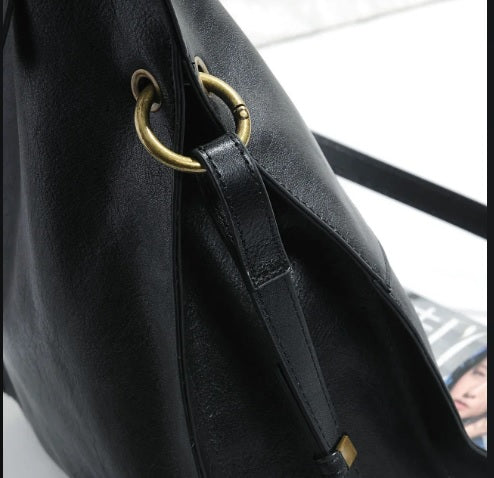 Antiqued brass O-ring hardware detail on leather bucket tote