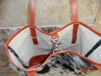 Close-up of clasp closure on black white salt pepper cowhide bucket shopper handbag