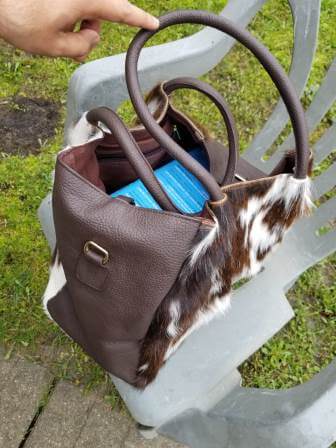Open top clasp closure detail on genuine brown and white hair-on cowhide leather hobo bag