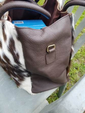 Close-up of dual leather handles and detachable long shoulder strap on brown white cowhide hobo bag