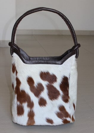 Tan and white cowhide leather bucket handbag with brown leather handles and magnetic closure – front view