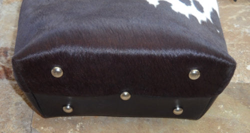 Close-up of reinforced metal rivet base on large brown white cowhide leather tote bag