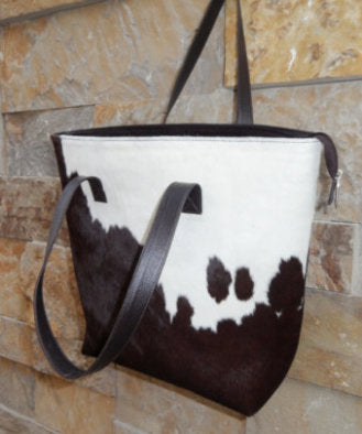 Side view of large genuine hair-on cowhide tote bag with reinforced metal rivet base