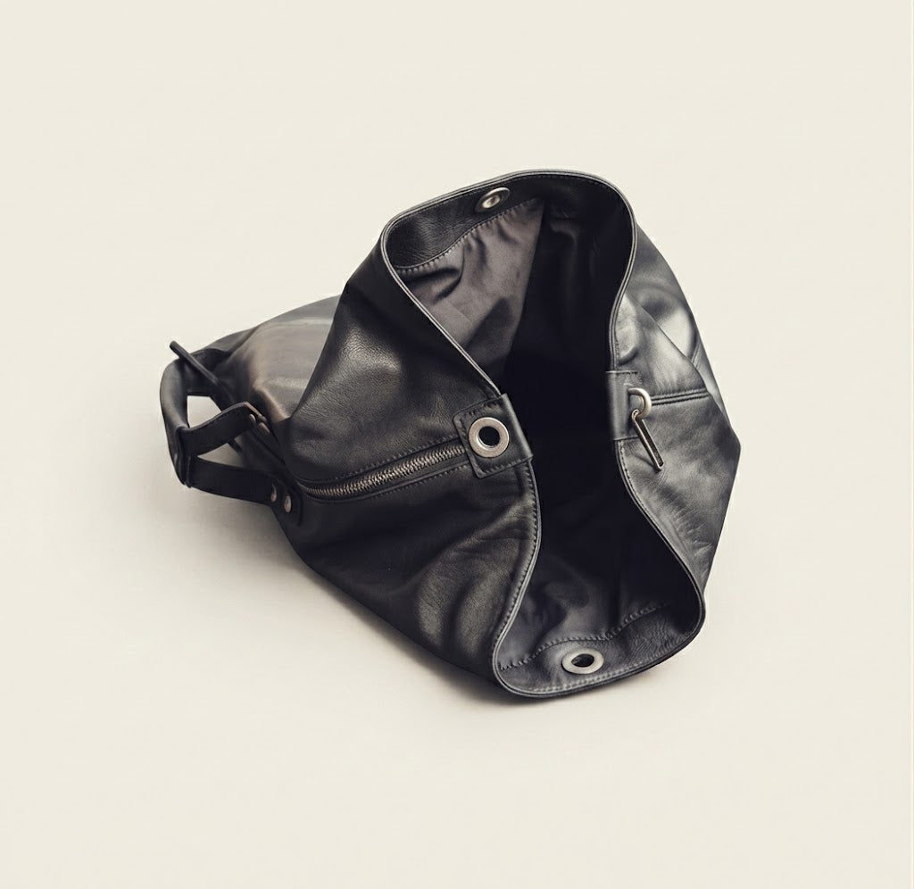 Grommet top closure detail on black leather duffle backpack