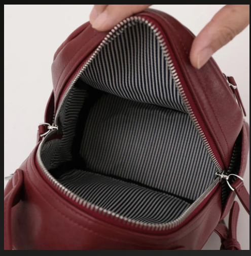Arched top handle detail on compact leather daypack