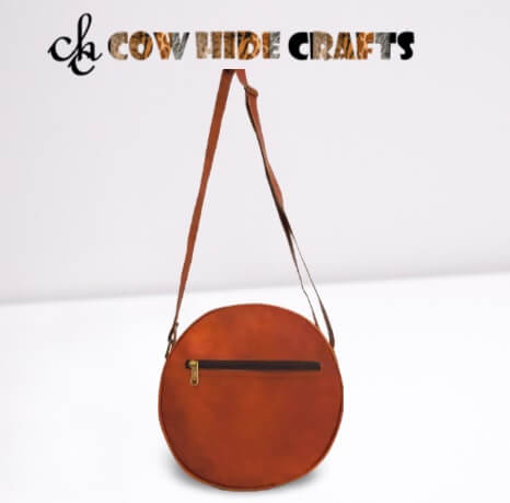 Outside pocket on tan leather round crossbody sling bag