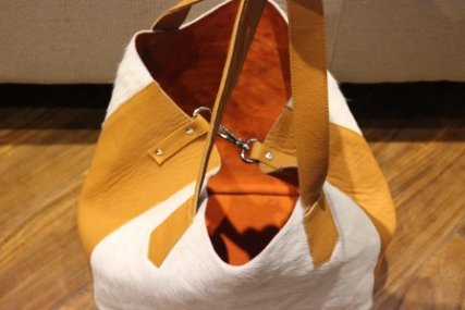 Close-up of genuine white hair-on cowhide panel on light brown textured leather shopper bag