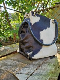 Side view of genuine black white hair-on cowhide square bucket bag showing structured 6 inch width