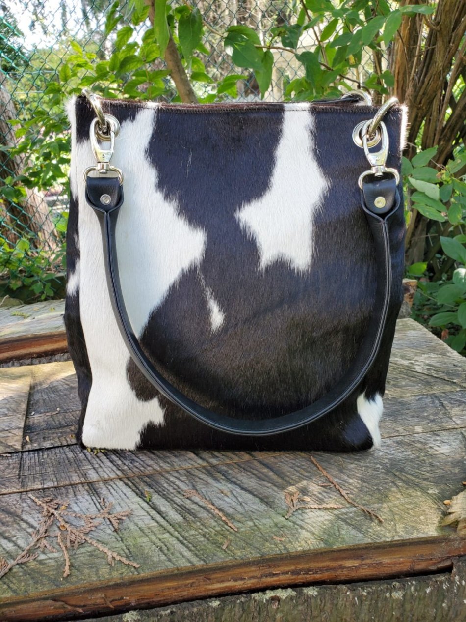 Square black and white cowhide leather bucket bag with magnetic closure and leather handles