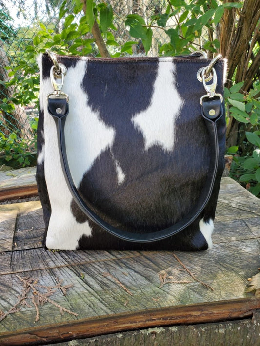 Square black and white cowhide leather bucket bag with magnetic closure and leather handles